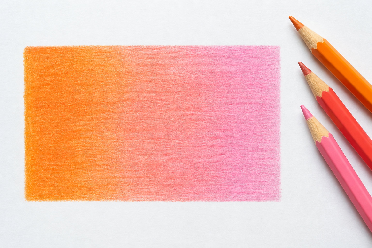 A close-up of a hand-colored gradient swatch on white paper smoothly fading from warm orange into soft pink, colored with pencils in even light layers, a few colored pencils resting beside it, bright